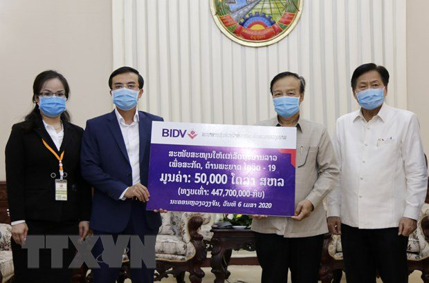 Representatives of BIDV present US$50,000 to the Lao Government in support of the countrys efforts to combat COVID-19. (Photo: VNA) 