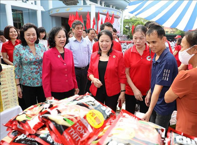 
Politburo member Truong Thi Mai (in red coat, left) visits a booth at the humanitarian market. (Photo: VNA) 
