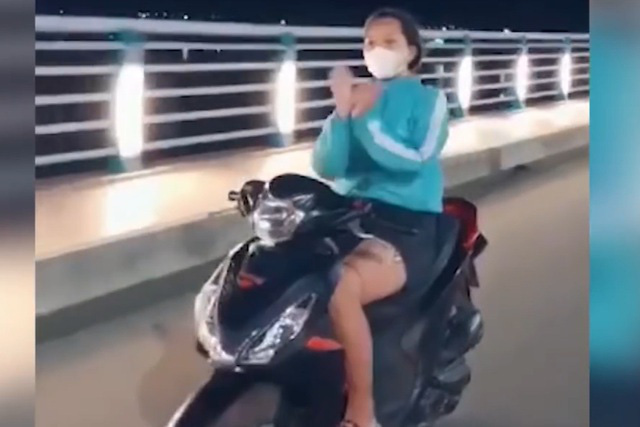 Đi xe máy thả hai tay múa quạt, cô gái bị phạt 7,4 triệu đồng - Ảnh 2.