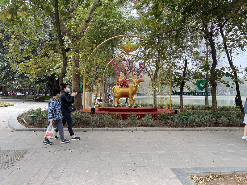Pedestrians enjoy walking around Hoan Kiem Lake. The road around the lake is also decorated with flowers and Golden Buffalo mascots.