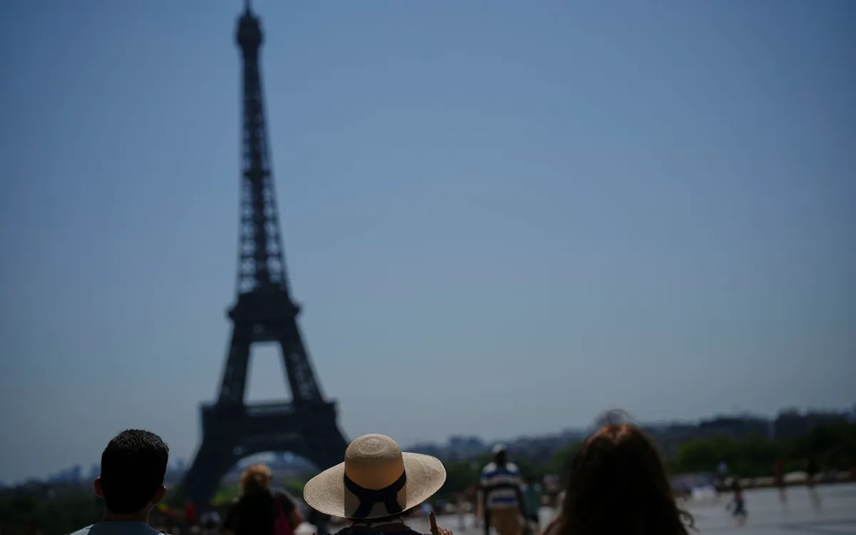 Khách du lịch chiêm ngưỡng tháp Eiffel từ xa (Ảnh: AP)