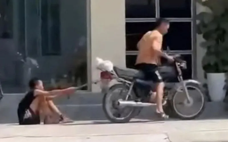 Cháu bé bị trói tay, xích chân kéo lê trên đường bằng xe máy Cháu bé bị trói tay, xích chân kéo lê trên đường bằng xe máy
