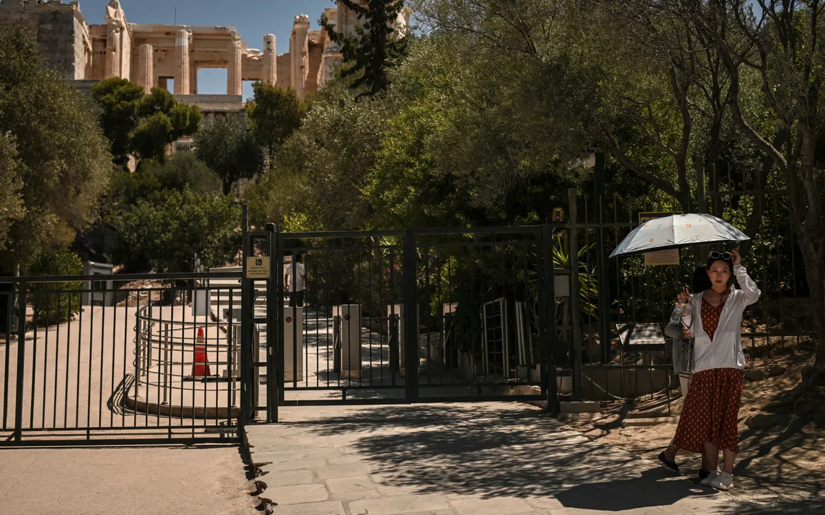 Du khách đứng bên ngoài di tích Acropolis giữa trời nắng nóng (Ảnh: AFP)