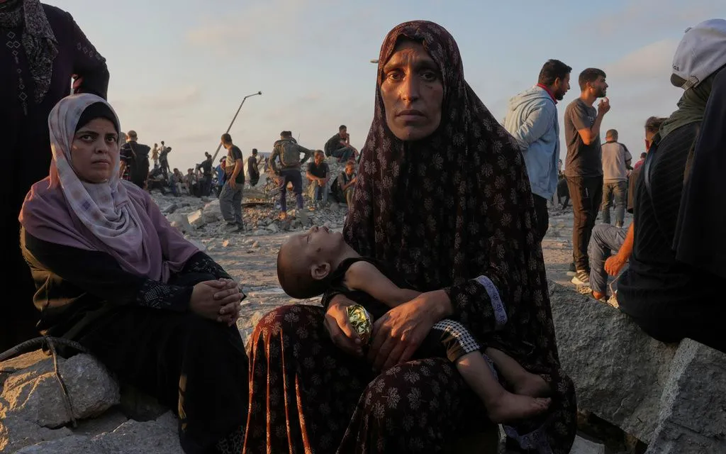 Người phụ nữ Palestine ngồi cùng con chờ xe viện trợ tại phía bắc Dải Gaza ngày 25/7/2025. (Ảnh: AP)