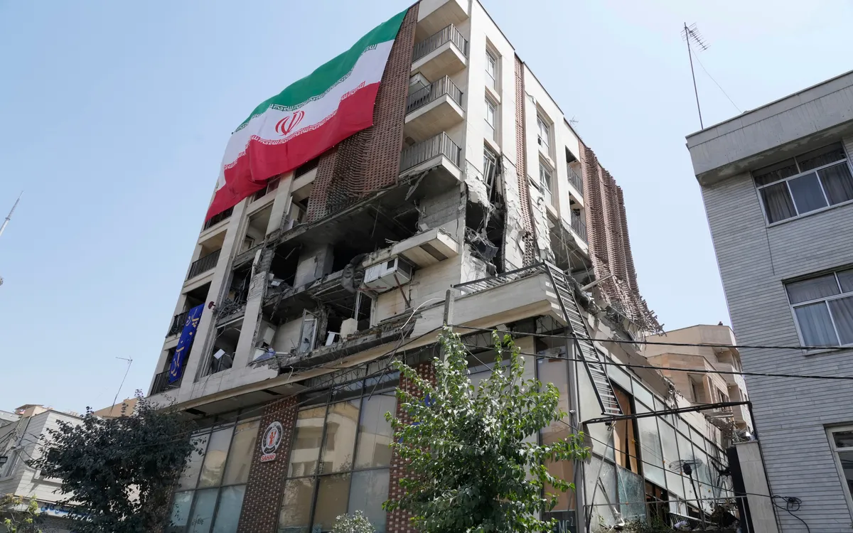 Lá cờ Iran phủ trên một tòa nhà dân cư bị trúng tên lửa trong cuộc không kích của Israel tại Tehran, ngày 25/6/2025 (Ảnh: AP)