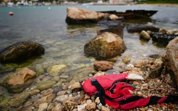 Áo phao nằm cạnh một con thuyền bị chìm trên bãi biển ở Lampedusa, Italy, năm 2024 (Ảnh: Victoria Jones/PA)