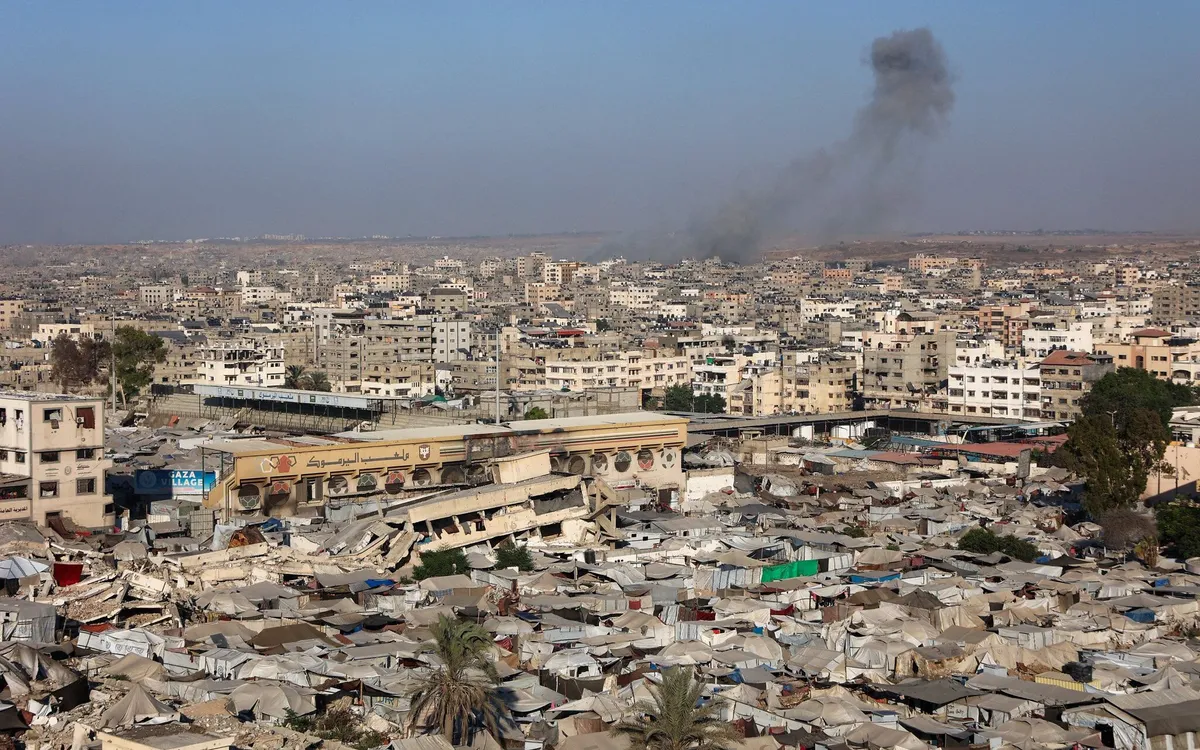 Quang cảnh một trại di tản tạm thời tại Sân vận động thể thao Yarmuk khi khói bốc lên trong các cuộc không kích của Israel vào thành phố Gaza ngày 4/9/2025 (Ảnh: AFP)