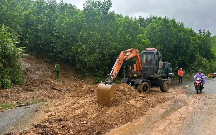 Lực lượng chức năng thu dọn vị trí bị sạt lở trên tuyến đường Quốc lộ 14G, xã Hòa Vang. (Ảnh: TTXVN phát)