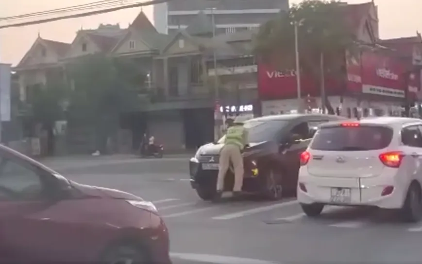 Tài xế không chấp hành hiệu lệnh, CSGT bị hất lên nắp capo. Ảnh cắt từ video clip. Tài xế không chấp hành hiệu lệnh, CSGT bị hất lên nắp capo. Ảnh cắt từ video clip.