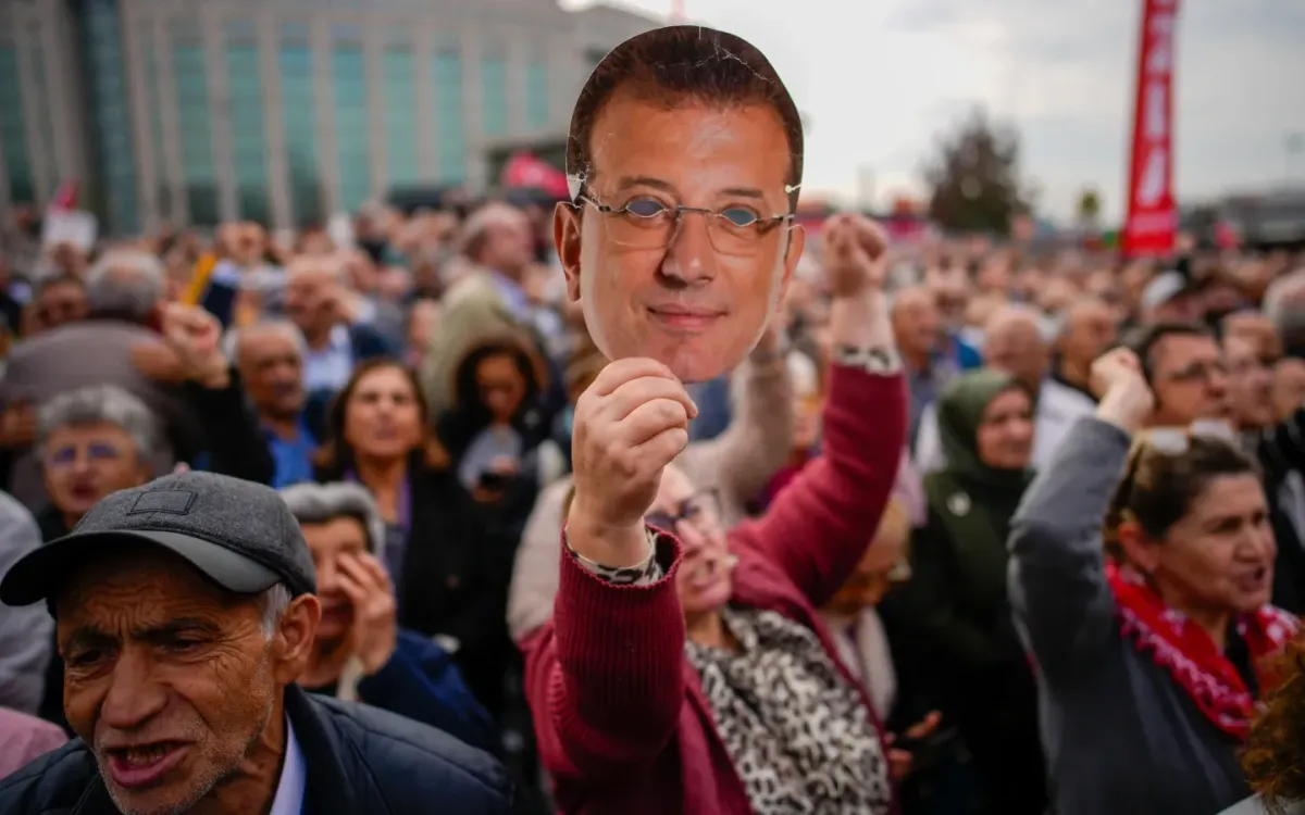 Một phụ nữ giơ chiếc mặt nạ in hình Thị trưởng Istanbul Ekrem Imamoglu trong cuộc biểu tình ủng hộ ông bên ngoài tòa Caglayan, ngày 26/10/2025 (Ảnh: AP)