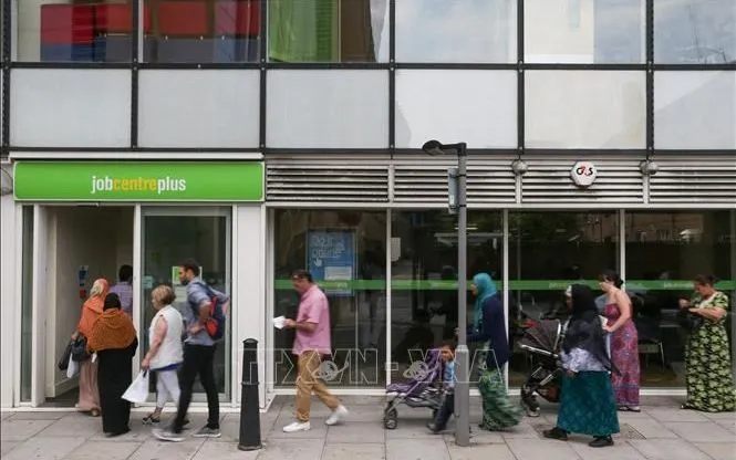 Người dân xếp hàng bên ngoài một trung tâm giới thiệu việc làm tại London, Anh. Ảnh: AFP/TTXVN
