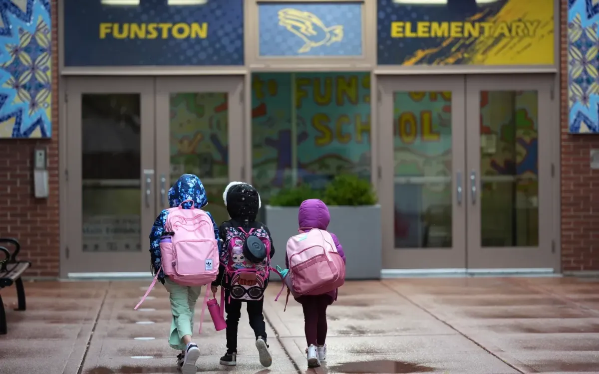 Ba chị em bước vào trường Tiểu học Funston ở khu Logan Square, Chicago, ngày 15/10/2025 (Ảnh: AP)
