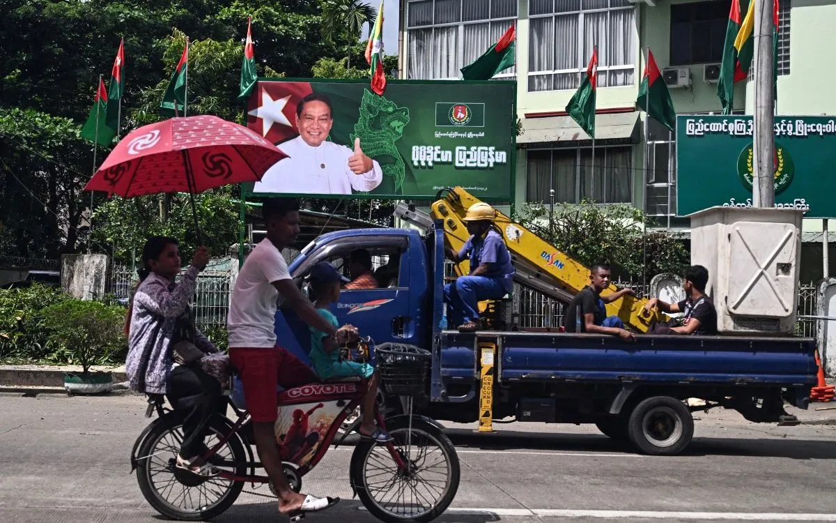 Người dân đi ngang pano tranh cử của ông Khin Yi, Chủ tịch đảng USDP thân quân đội, tại Yangon, ngày 27/10/2025 (Ảnh: AFP)