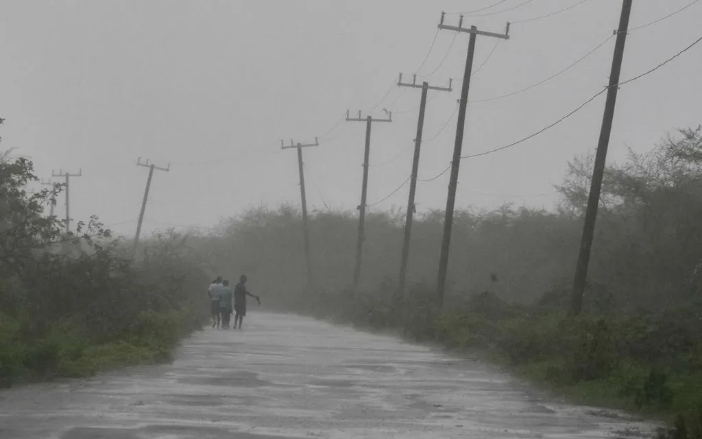 Người dân đi bộ dọc theo một con đường trong lúc bão Melissa quét qua Rocky Point, Jamaica, ngày 28/10/2025 (Ảnh: AP)