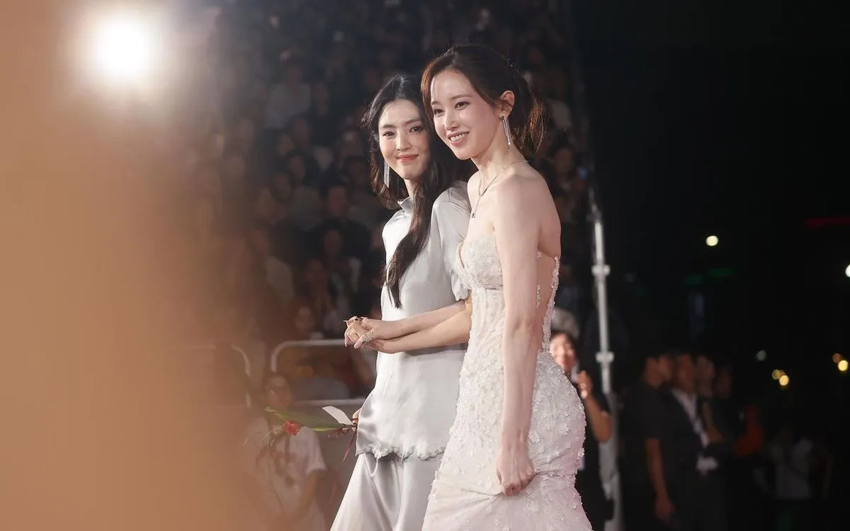 Diễn viên Han So Hee (bên trái) và Jeon Jong Seo nắm tay nhau trên thảm đỏ LHP quốc tế Busan lần thứ 30. (Ảnh: Yonhap)