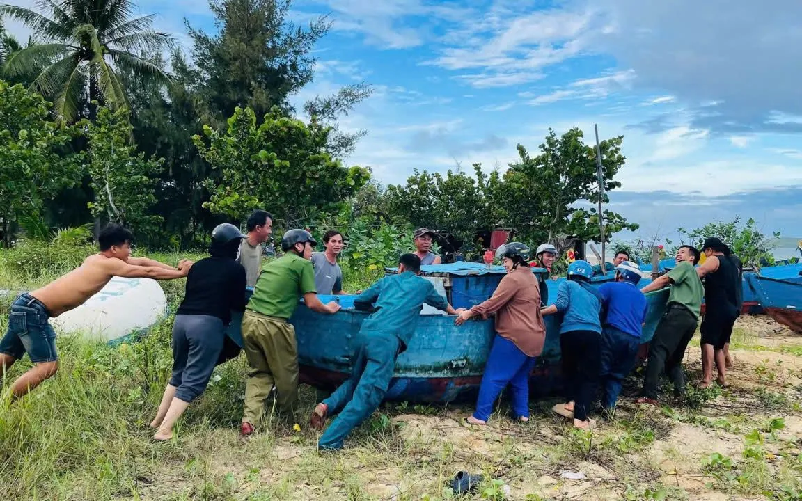Lực lượng chức năng hỗ trợ người dân đưa tàu cá từ biển vào bờ để tránh bão.