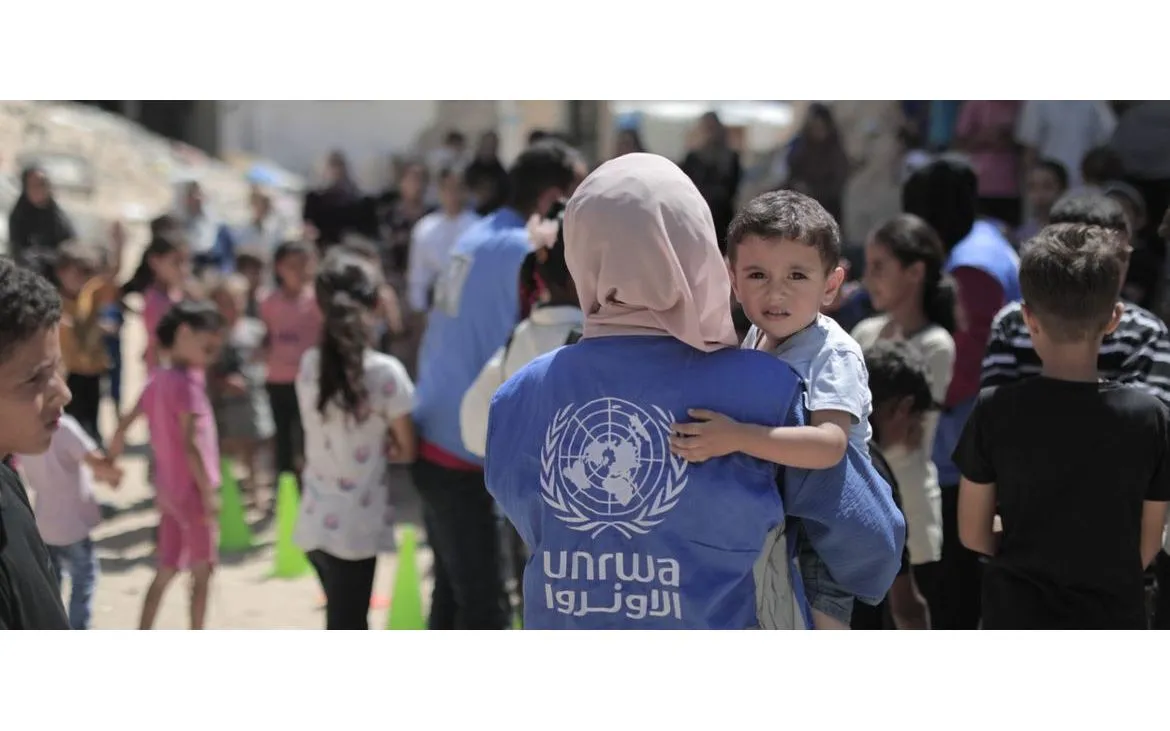 Nhân viên UNRWA bế một bé trai tại Gaza (Ảnh: UNRWA)