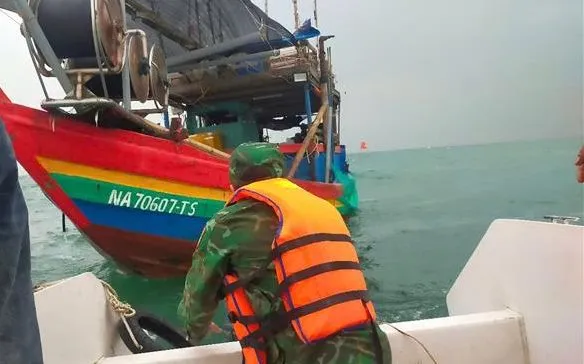 Lực lượng cứu nạn của Đồn Biên phòng Diễn Thành tiếp cận vị trí tàu cá bị chìm, đưa 3 ngư dân gặp nạn lên ca nô an toàn. Ảnh: TTXVN

