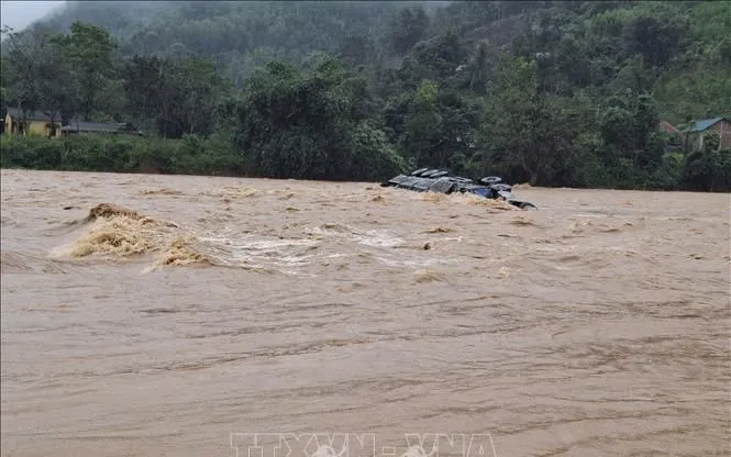 Chiếc xe container vượt ngầm tràn, lái xe bị lũ cuốn trôi mất tích. Ảnh: TTXVN