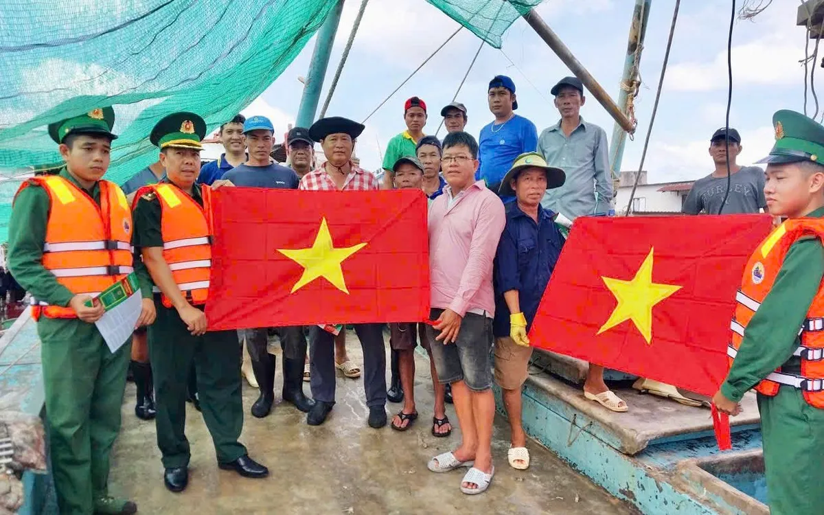 Lực lượng Đồn Biên phòng Bến Đá phát tờ rơi tuyên truyền chống khai thác IUU và tặng cờ Tổ quốc cho bà con ngư dân.