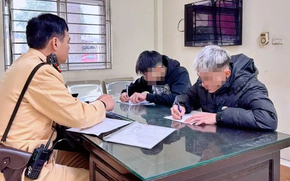 Cảnh sát làm việc với hai thanh niên vi phạm.