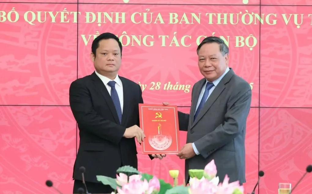Phó Bí thư Thường trực Thành ủy Hà Nội Nguyễn Văn Phong trao quyết định của Ban Thường vụ Thành ủy Hà Nội và tặng hoa chúc mừng ông Vũ Minh Tuấn.