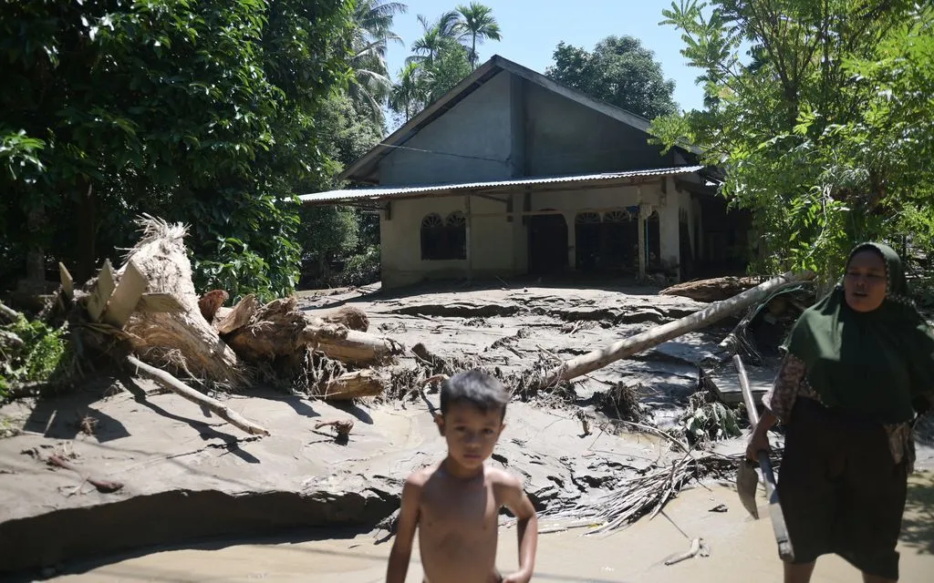 Người dân đứng bên ngoài một ngôi nhà bị ảnh hưởng bởi lũ lụt ở Pidie Jaya, tỉnh Aceh, Indonesia, ngày 29/11/2025. (Ảnh: AP)