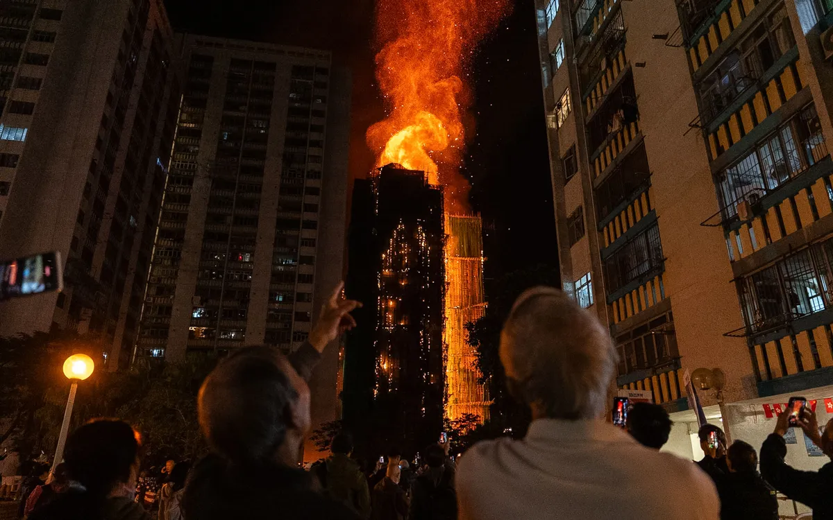 Người dân chứng kiến ngọn lửa bao trùm tòa nhà tại khu chung cư Wang Fuk Court ở Hong Kong (Trung Quốc), ngày 26/11/2025 (Ảnh: AP)