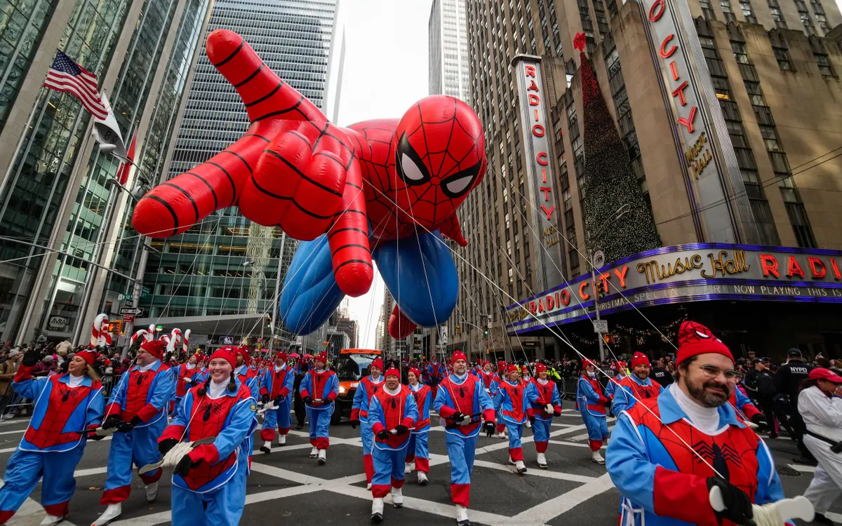 Nhân viên điều khiển bóng Spider-Man đi qua Radio City Music Hall trong buổi diễu hành Macy’s Thanksgiving tại New York ngày 27/11/2025. (Ảnh: AP)