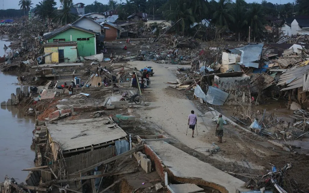 Người sống sót đi qua khu vực bị lũ quét tại Aceh Tamiang, đảo Sumatra, Indonesia, ngày 4/12/2025. (Ảnh: AP)