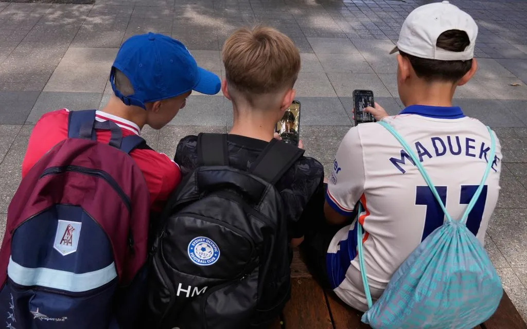 Một nữ sinh dùng điện thoại khi đi cùng nhóm bạn tại Sydney (Ảnh: AP)