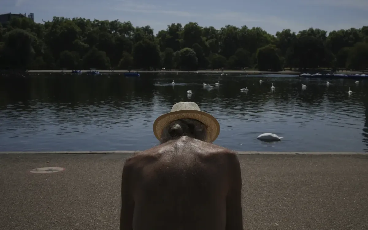 Một người đàn ông ngồi dưới nắng tại công viên ở London giữa đợt nắng nóng (Ảnh: AP)