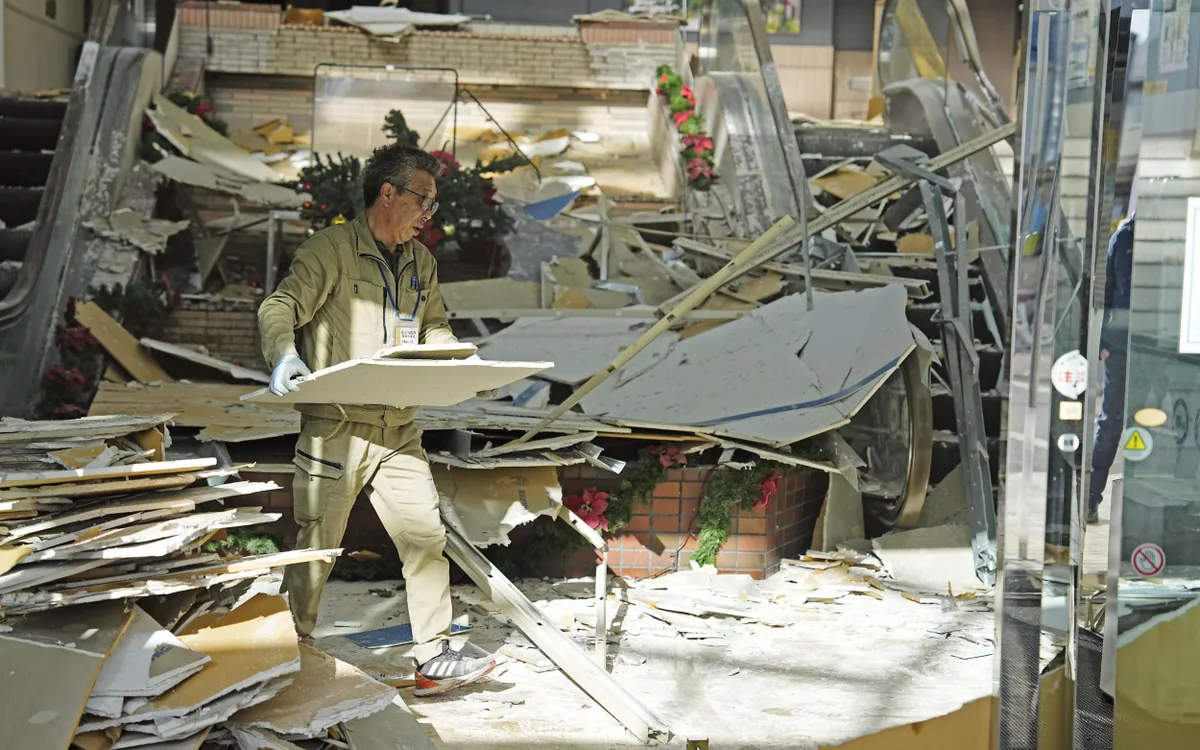 Một người đàn ông dọn dẹp đống đổ nát tại một cơ sở thương mại ở Hachinohe sau trận động đất mạnh hôm 8/12 ở tỉnh Aomori, miền Bắc Nhật Bản (Ảnh: Kyodo News/AP)