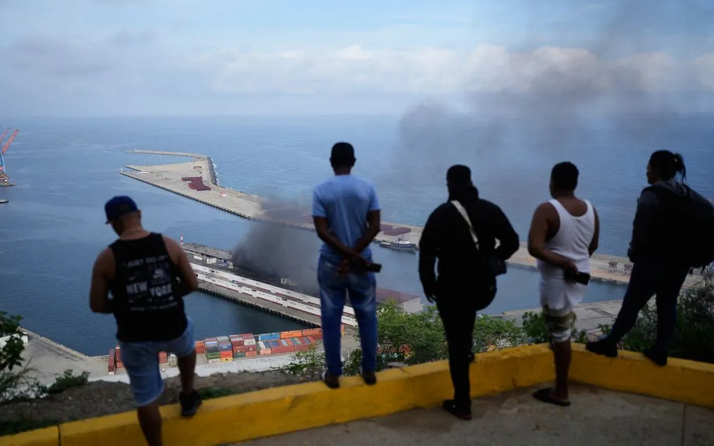 Người dân theo dõi khói bốc lên từ cảng La Guaira, Venezuela, sau các vụ nổ, ngày 3/1/2026 (Ảnh: AP)