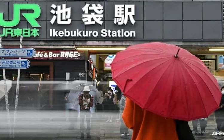 Người dân che ô tránh mưa bên ngoài ga Ikebukuro - một trong 30 nhà ga thuộc tuyến đường sắt Yamanote tại Tokyo. (Ảnh: AFP)