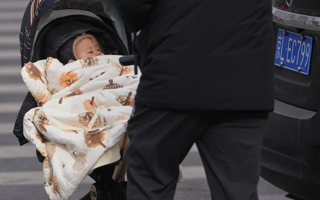 Người đàn ông đẩy xe nôi chở trẻ nhỏ trên đường phố Bắc Kinh, ngày 19/1/2026 (Ảnh: AP)