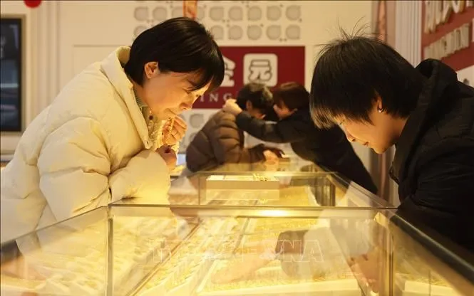 Khách hàng chọn mua trang sức vàng tại cửa hàng ở Chiết Giang, Trung Quốc. Ảnh: THX/TTXVN