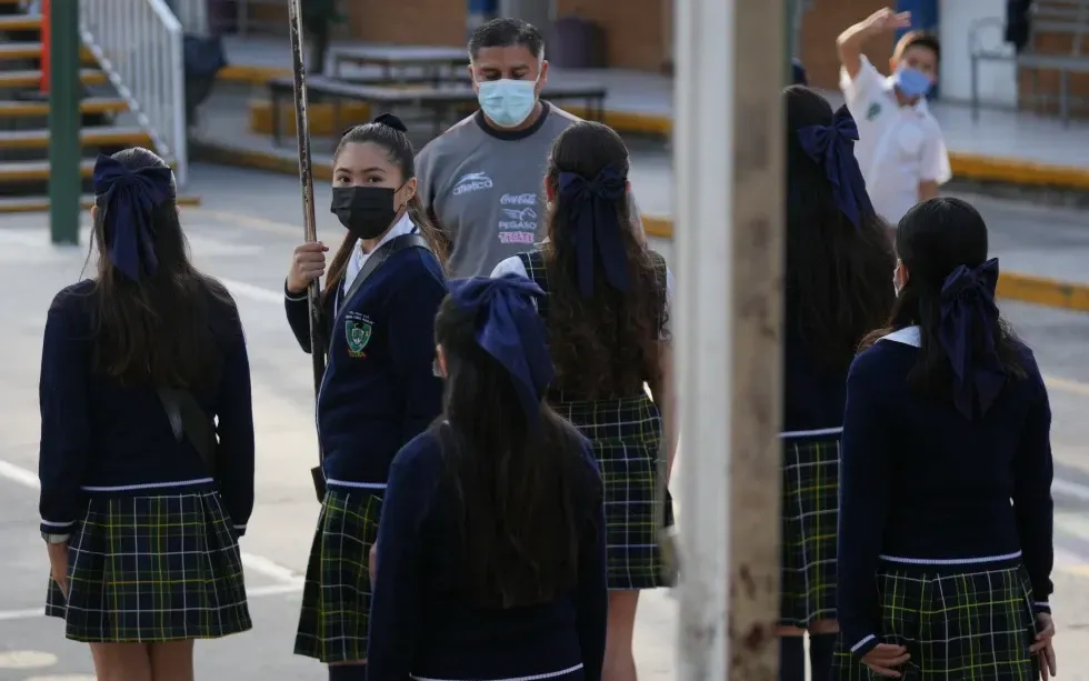 Học sinh v&agrave; gi&aacute;o vi&ecirc;n đeo khẩu trang bắt buộc trong lễ ch&agrave;o cờ tại một trường c&ocirc;ng lập ở Guadalajara, Mexico, ng&agrave;y 5/2/2026 (Ảnh: AP)