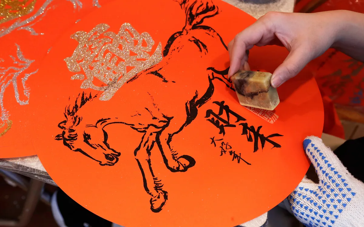 Một nghệ nhân đóng dấu lên đồ trang trí truyền thống phục vụ Tết Nguyên đán tại chợ Dihua ở Đài Bắc, Đài Loan (Trung Quốc), ngày 15/2/2026 (Ảnh: AP)