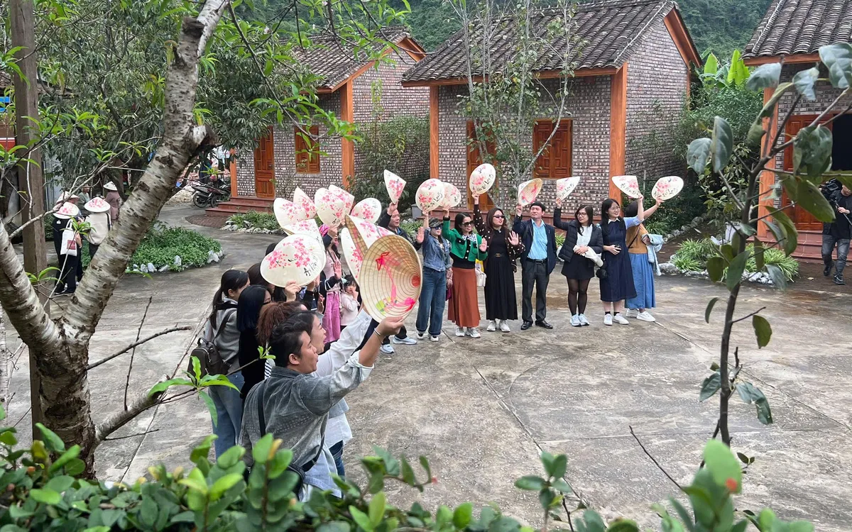 Du khách chụp ảnh lưu niệm trong làng du lịch.