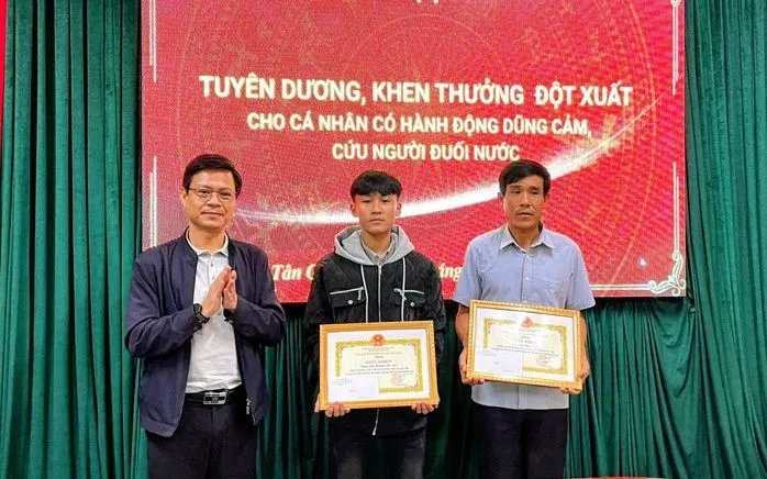 Ông Trần Thanh Hải - Chủ tịch UBND xã trao tặng Giấy khen cho hai cha con ông Cao Hữu Tình. Ảnh: NLĐ