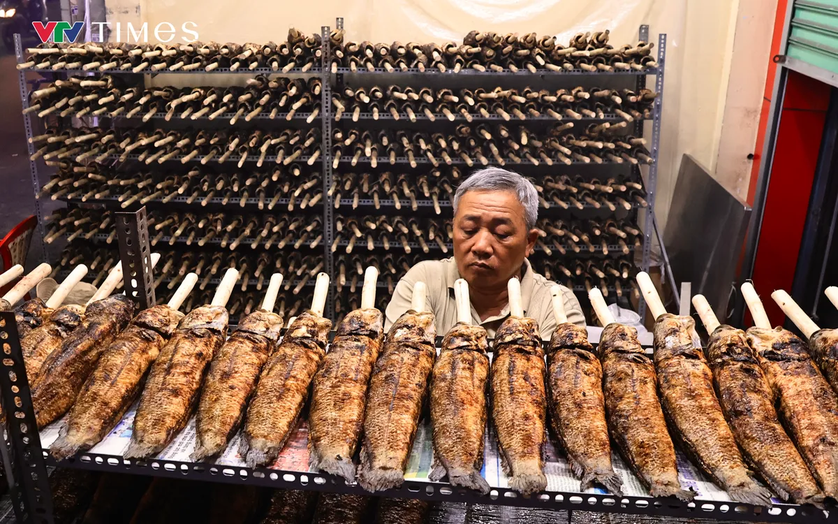 Ông Lê Đức Dưỡng tỉ mỉ sắp xếp cá đã nướng sẵn lên kệ để chuẩn bị cho ngày vía Thần Tài ngày mai (10/1 âm lịch).