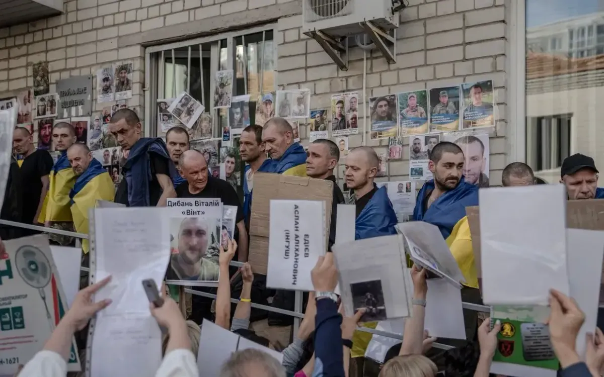 Các tù binh chiến tranh Ukraine được trả tự do đang xem chân dung những binh sĩ mất tích hoặc bị bắt giữ để giúp người thân của họ tìm kiếm người còn sống, ngày 10/6/2025 (Ảnh: AFP)