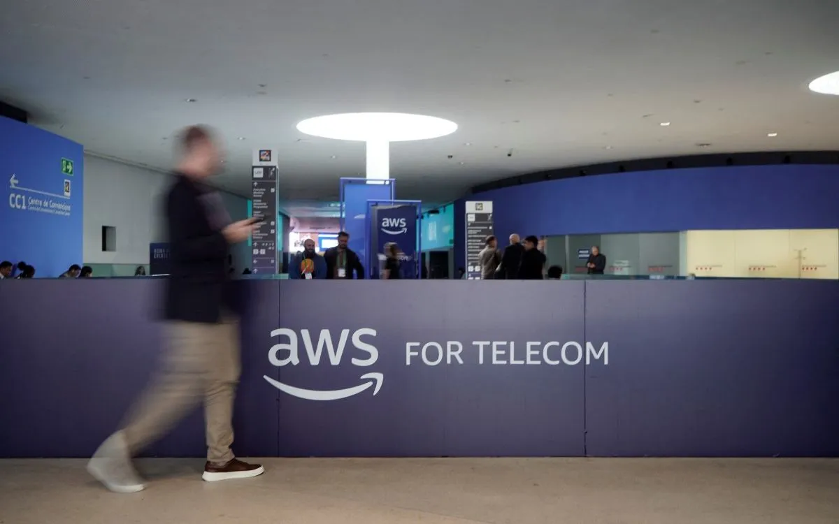 Khách tham quan đi ngang logo Amazon Web Services (AWS). (Ảnh: AFP)