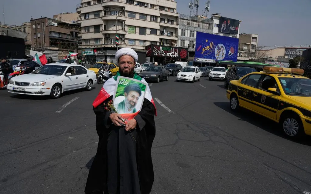 Một giáo sĩ cầm tấm ảnh của Lãnh tụ tối cao Iran Ayatollah Mojtaba Khamenei để ủng hộ chính phủ tại trung tâm Tehran, ngày 14/3/2026 (Ảnh: AP)