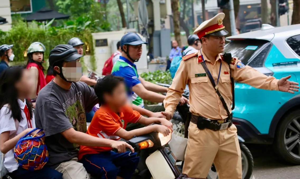 Hà Nội: Xử phạt nhiều phụ huynh không đội mũ bảo hiểm cho con khi đi xe máy - Ảnh 1.