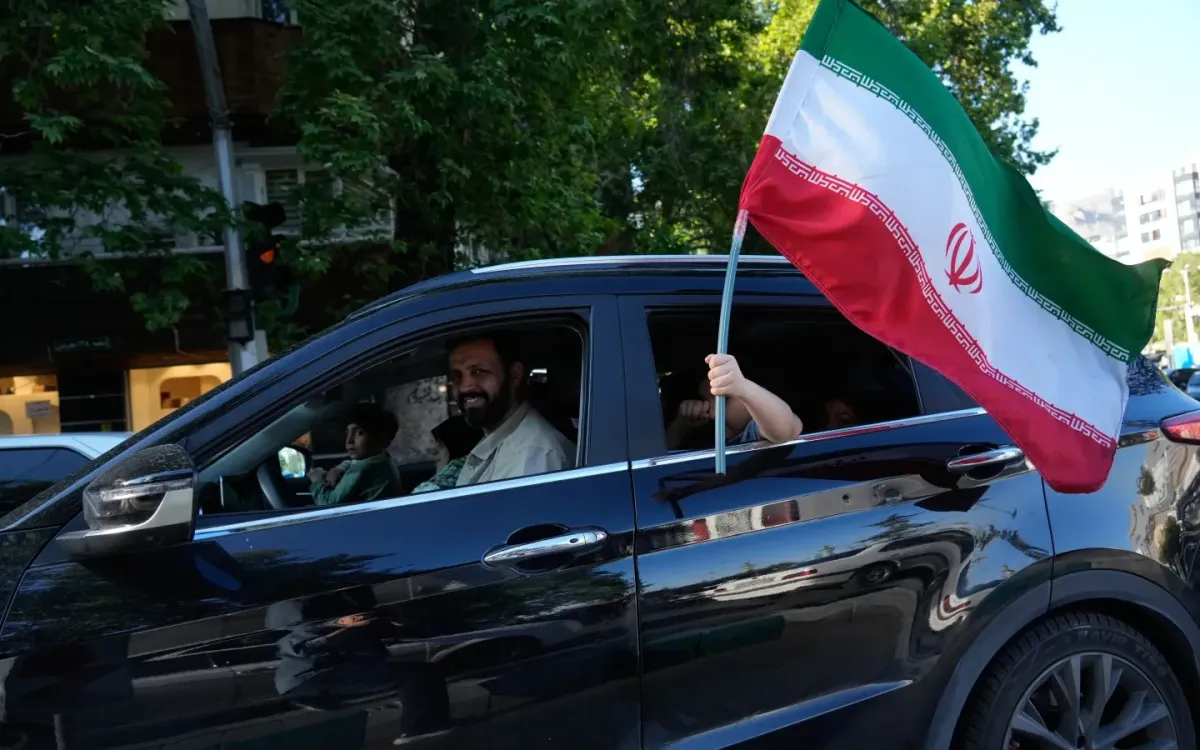 Một trẻ em cầm quốc kỳ Iran qua cửa sổ ô tô ở phía Bắc Tehran, Iran, ngày 1/5/2026. (Ảnh: AP)