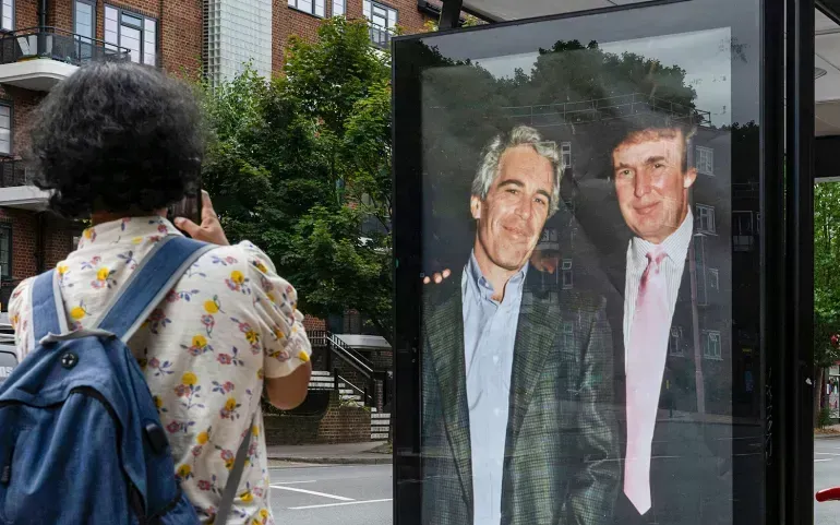 Các nhà hoạt động dán tấm áp phích có hình Tổng thống Donald Trump và Jeffrey Epstein gần đại sứ quán Hoa Kỳ tại London, Anh, ngày 17/7/2025 (Ảnh: AP)