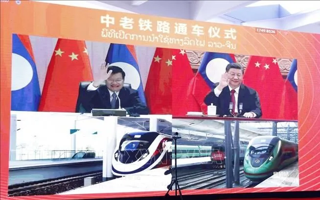 Lãnh đạo hai nước vẫy tay chào hai đoàn tàu đầu tiên đang xuất phát khỏi ga Vientiane và ga Côn Minh (Ảnh: TTXVN)