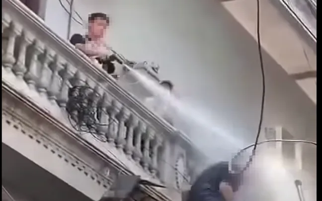 Người đàn ông xịt nước vào một công nhân làm việc trên cao. (Ảnh cắt từ clip)